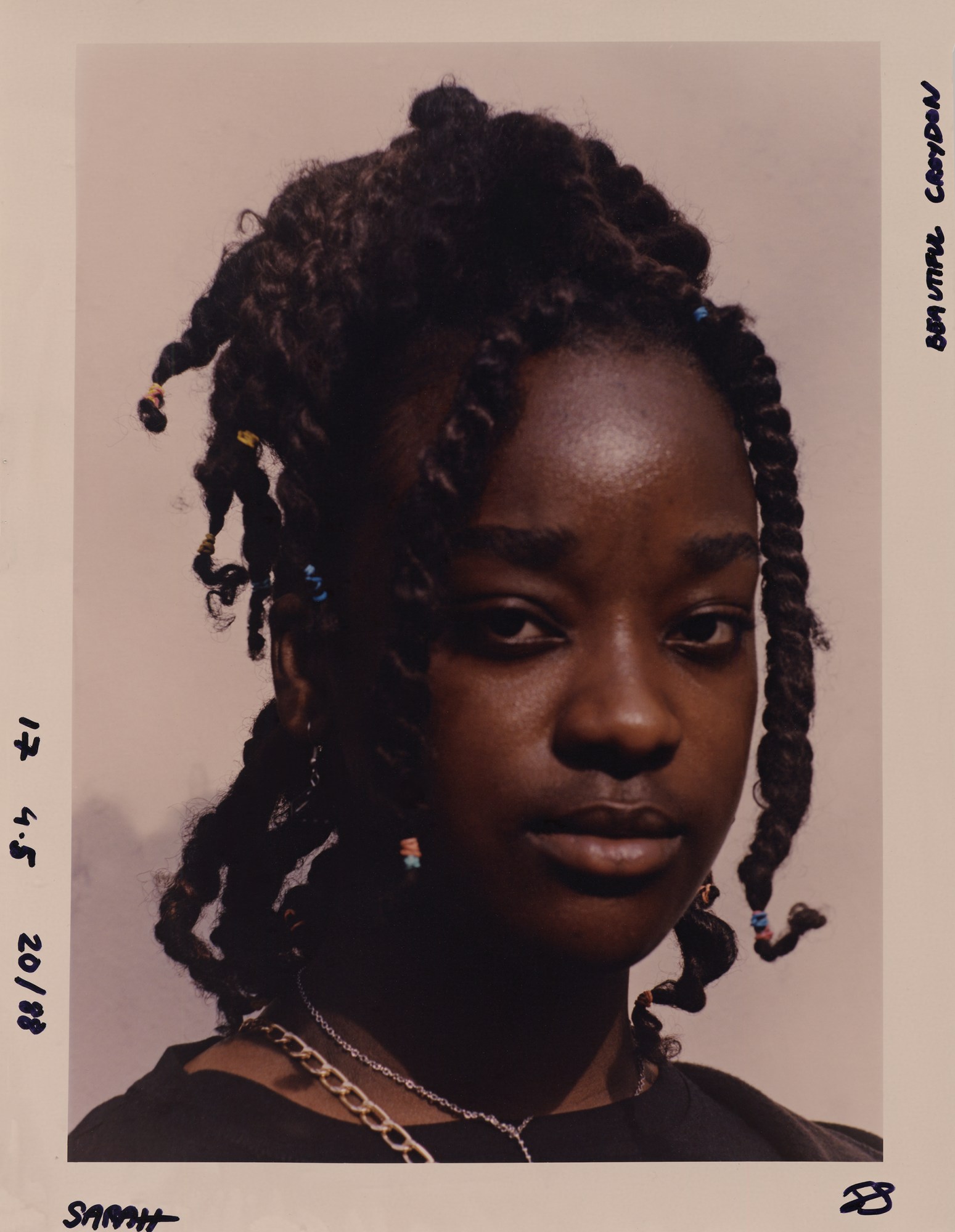 portrait of a young woman wearing a necklace and her her tied with colourful bands