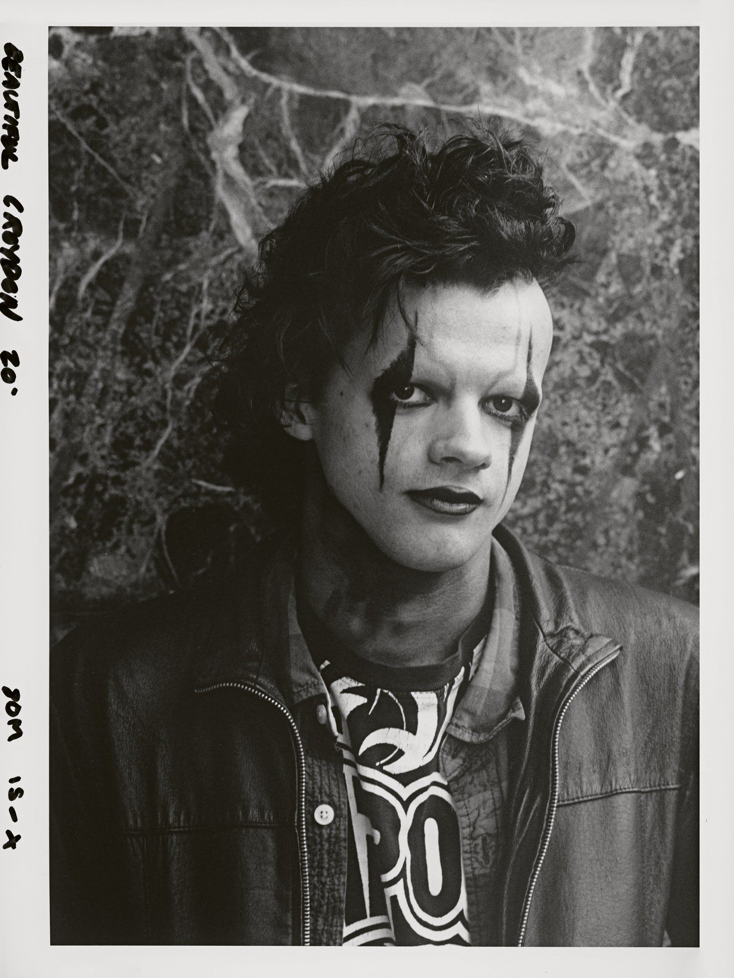 a young man wearing a leather jacket with gothic makeup on