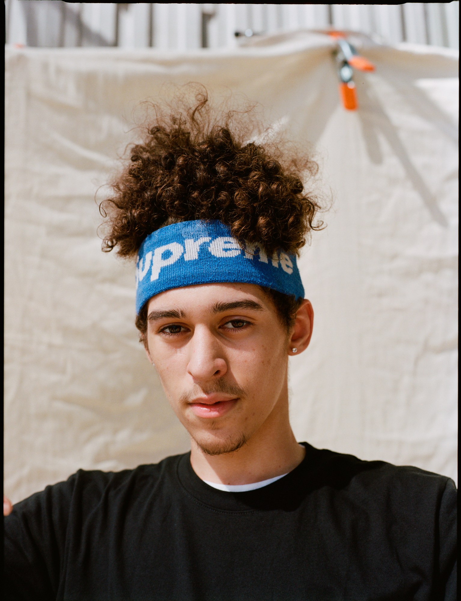 a portrait of a skateboarder wearing a supreme sweatband