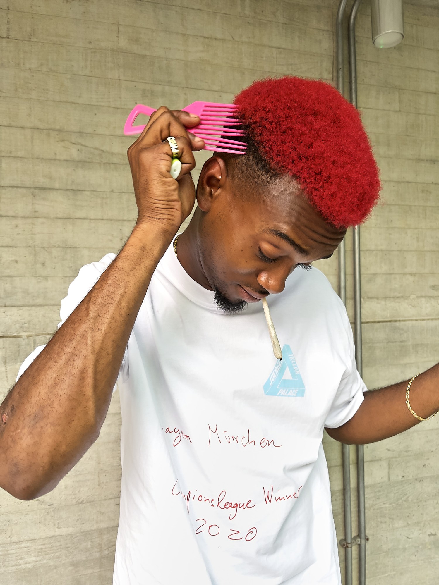 a man with dyed red hair wearing a palace t-shirt, smoking