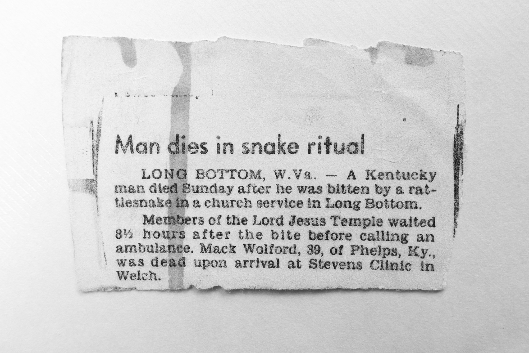 a newspaper cutout about a man who died by snake poisoning