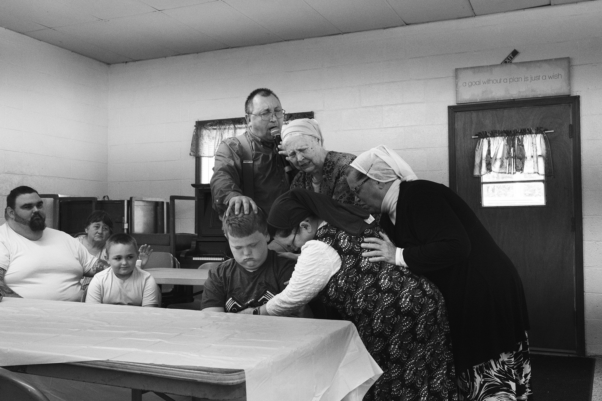 a group of adults pray over a young boy