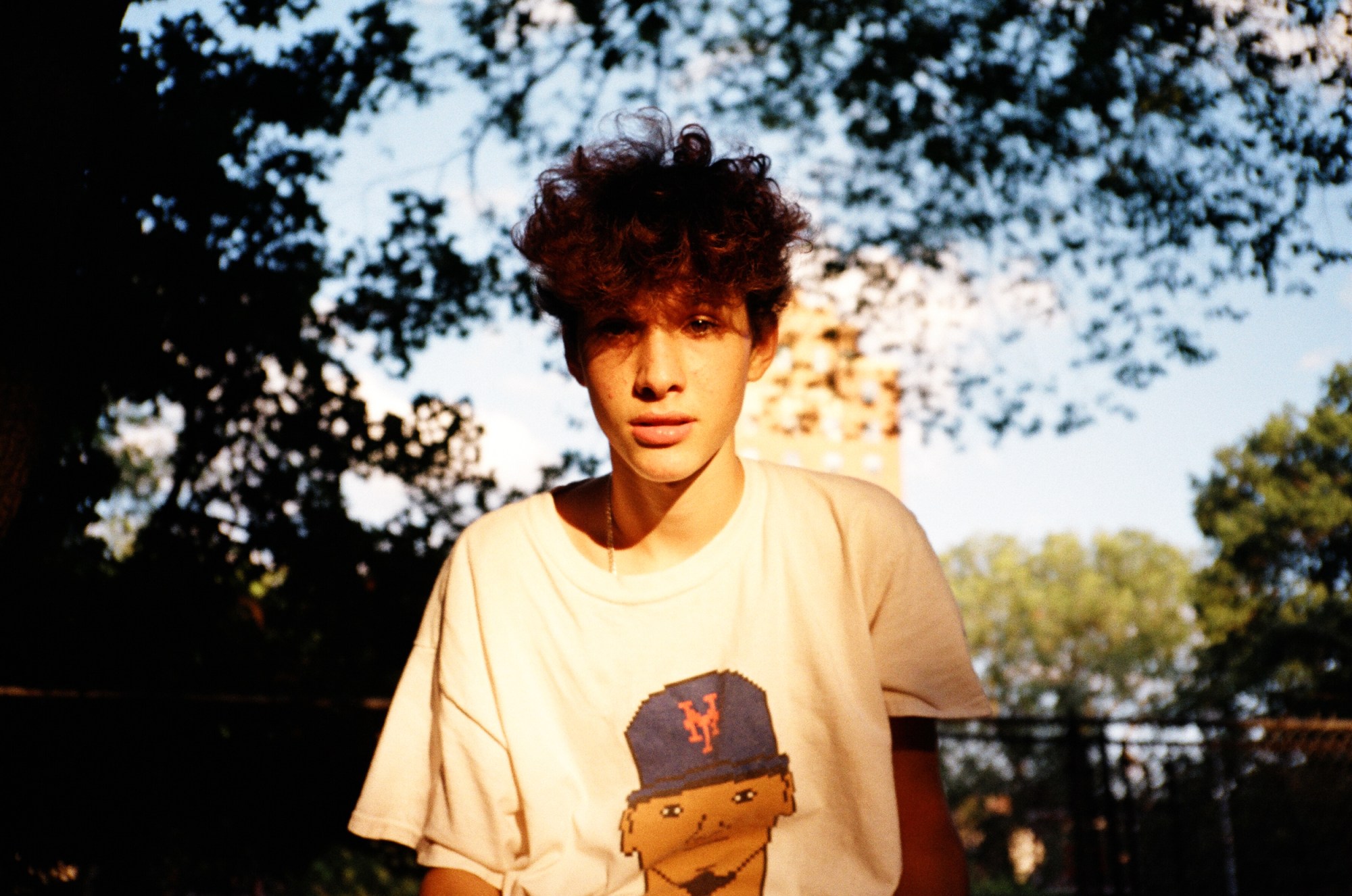 a young man with messy hair sat in a park