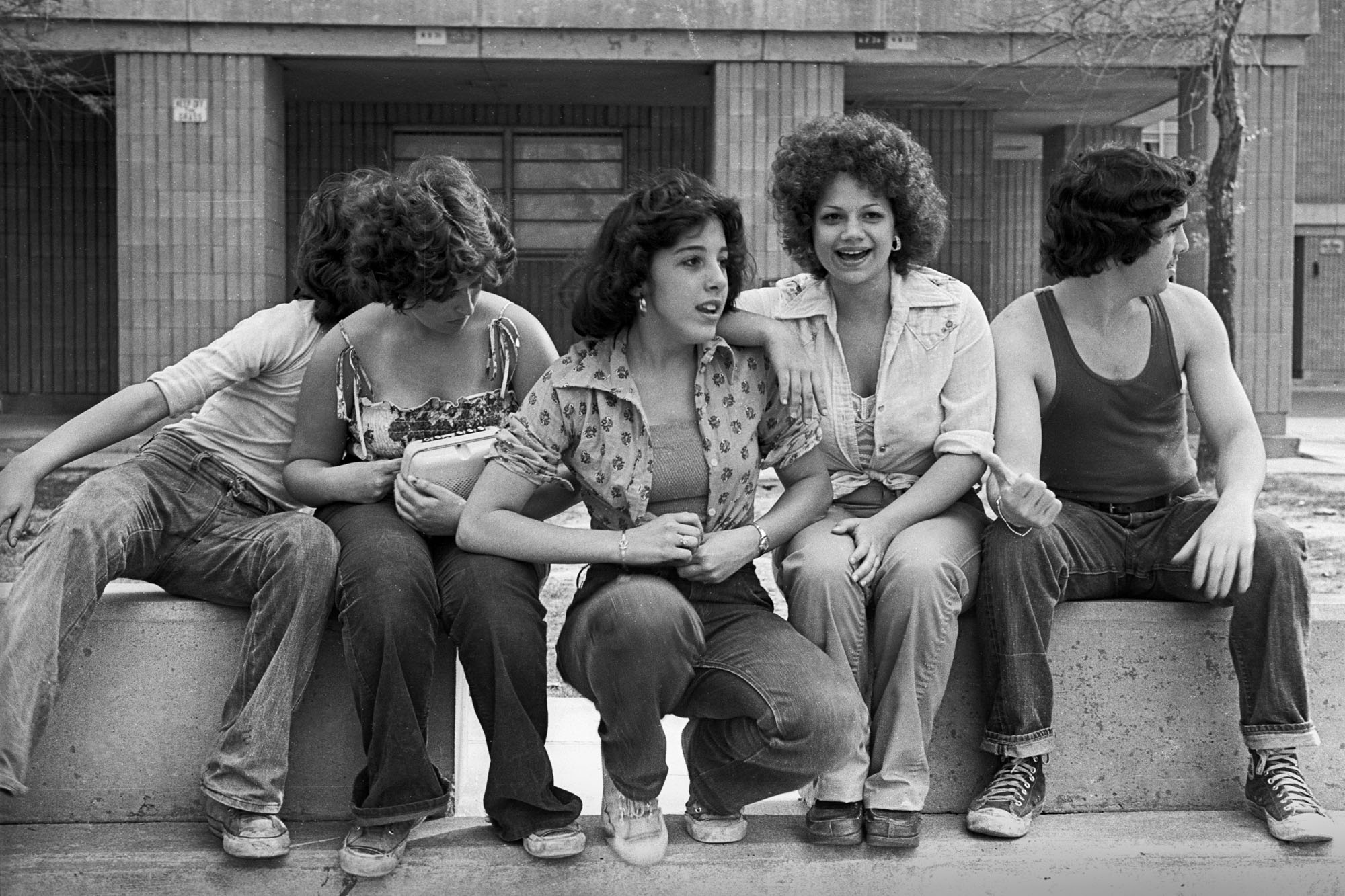 a group of young women and one man sat on concrete blocks