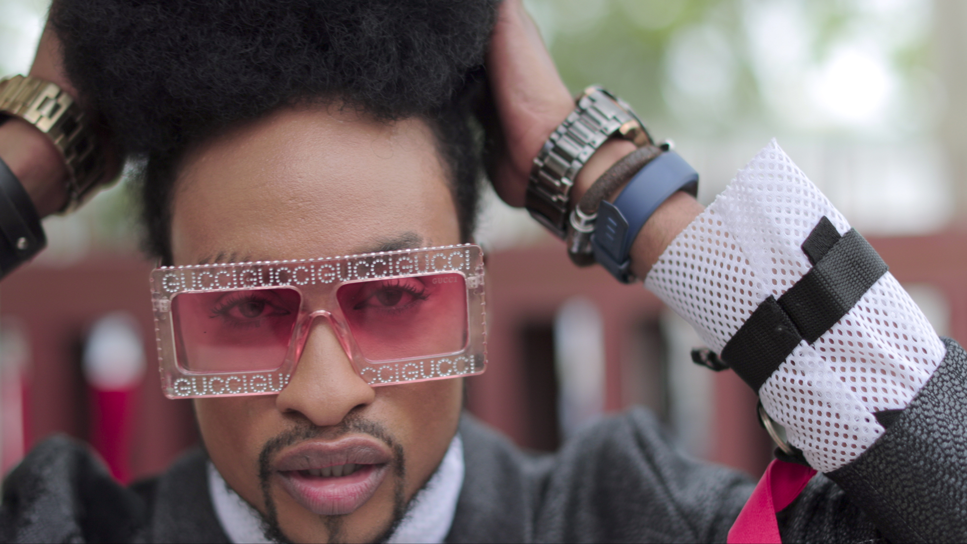 a man with a goatie wears large square pink Gucci sunglasses