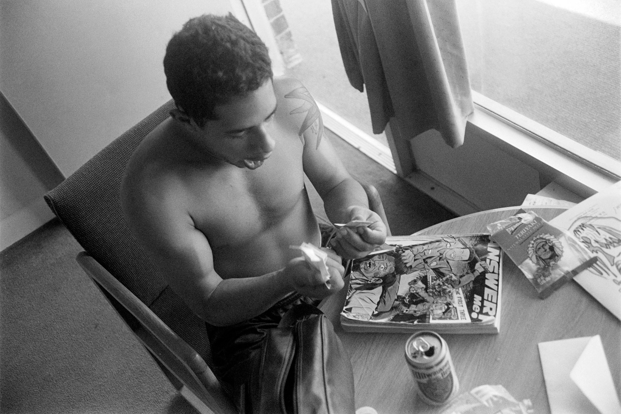 a topless man holding smoking paraphernalia over a book