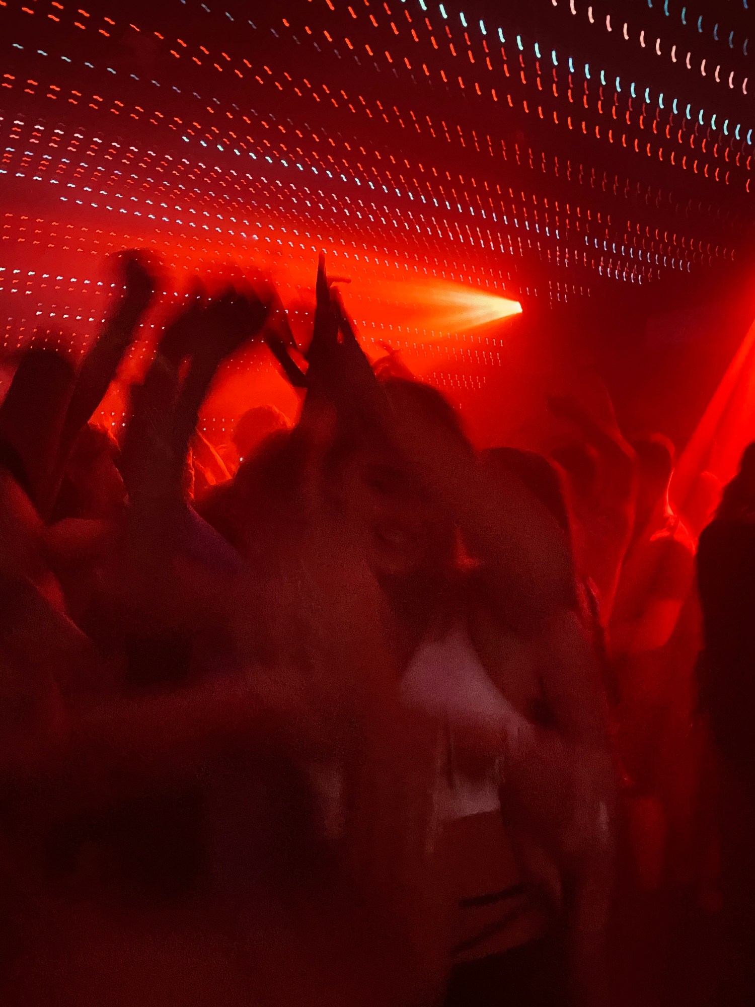 Figures dancing in a club under red and white strobe lights.