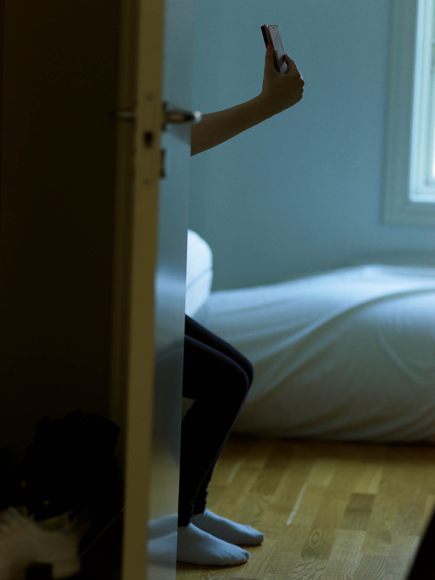 a person's arm can be seen outstretched behind a door, likely taking a photo of themselves