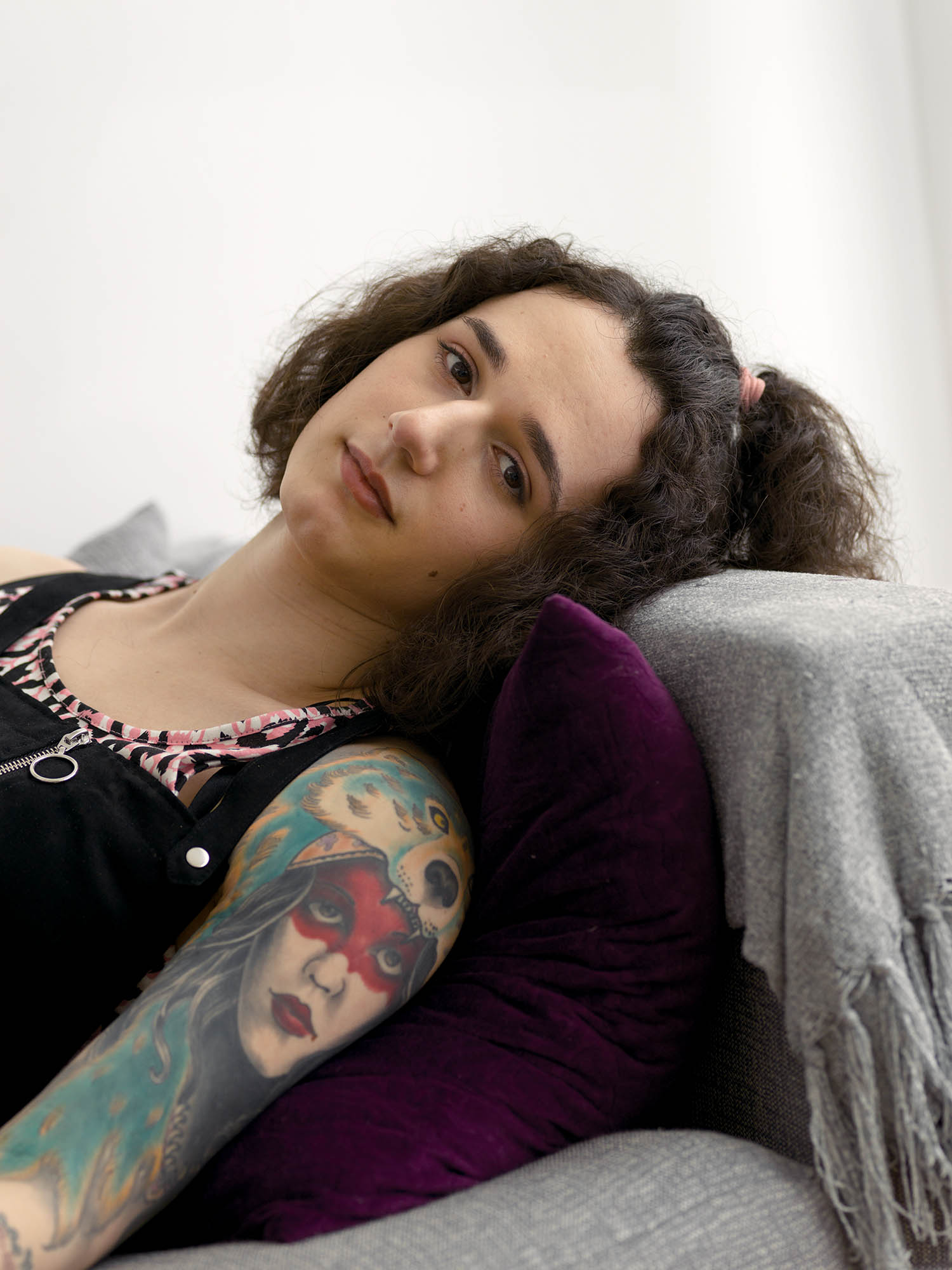 a woman with tattoos up her right arm lies on a sofa