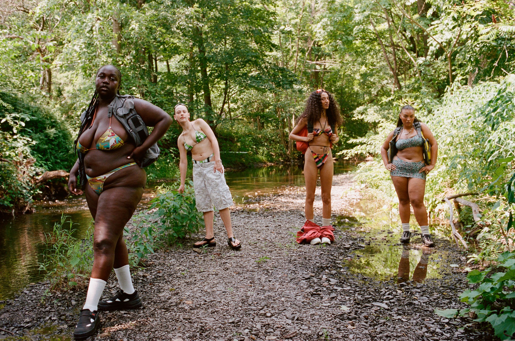 Four models wearing swimsuits by Paloma Elsesser x Dos Swim, stood on a mountain trail