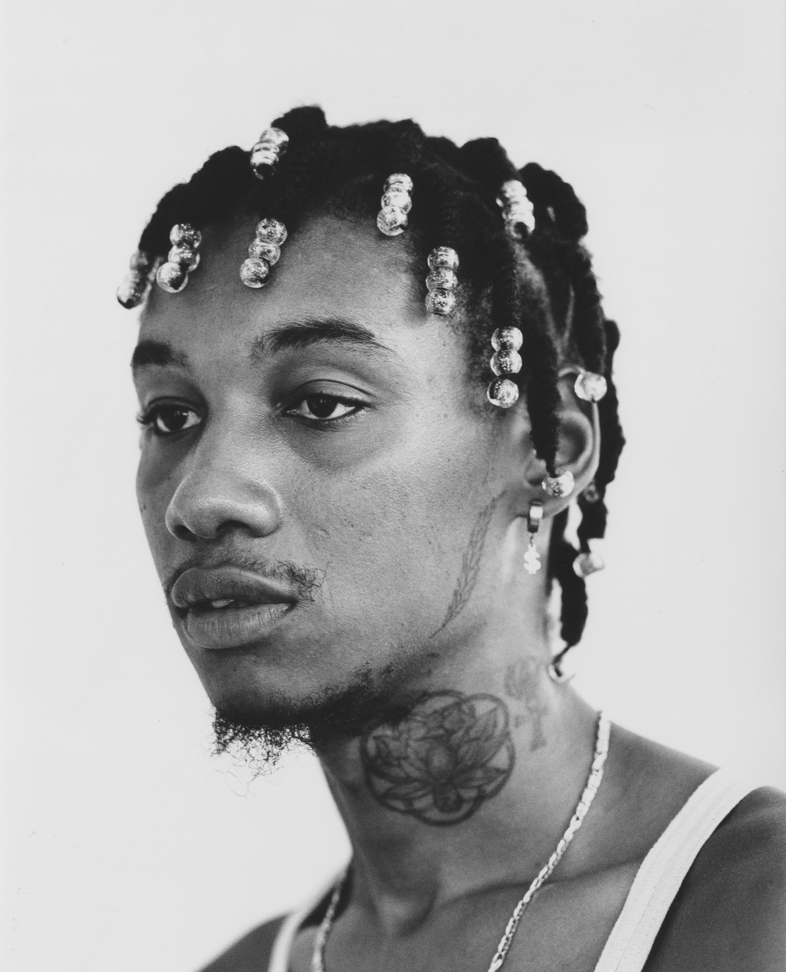 a young man with braids, neck tattoos and facial hair