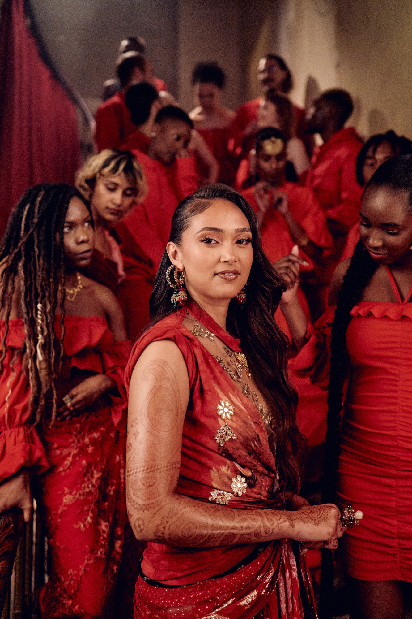 lots of women dressed in all red, joy crookes in the foreground wearing a red sari and henna tattoos