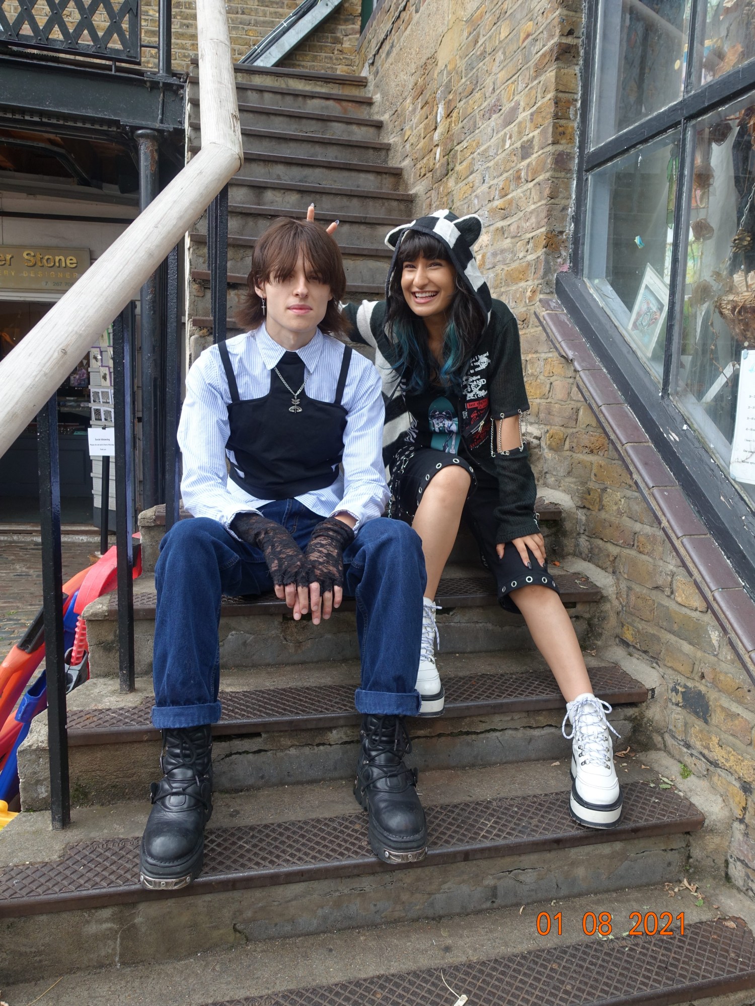 Two people sat on steps wearing industrial/gothy outfits