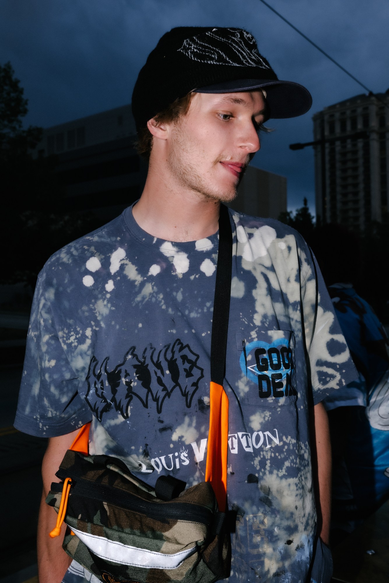 evan erickson with a camo backpack and upcycled clothes he designed by blake lewis