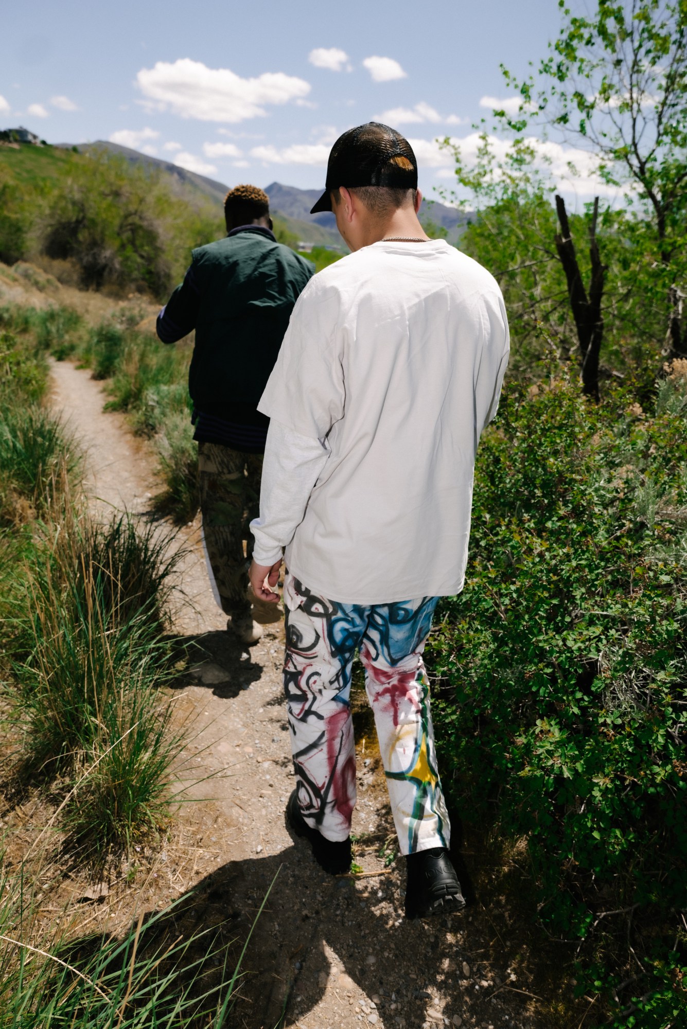 two boys walking on a trail in front of mountains in utah by blake lewis