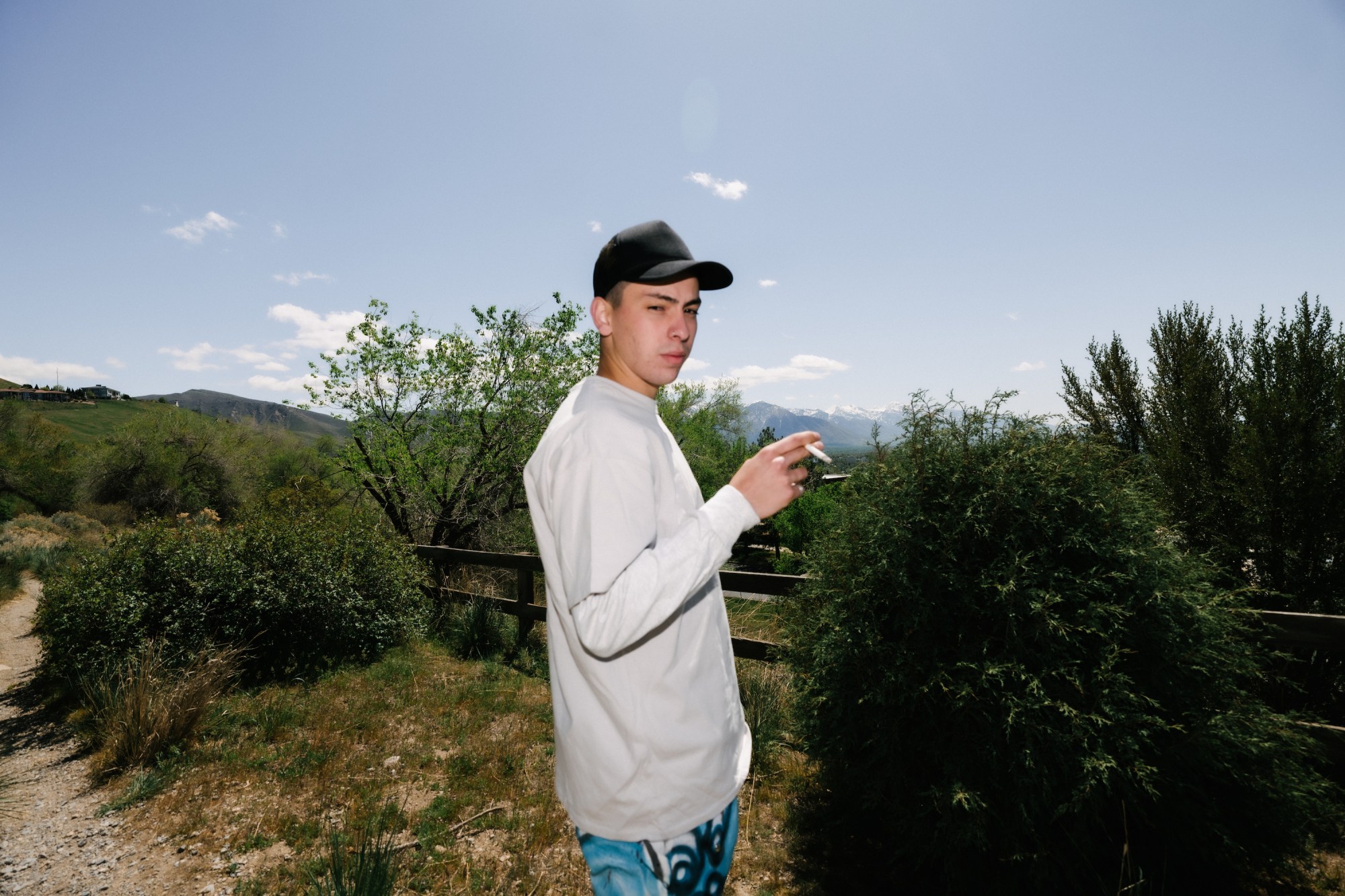 a portrait of mario cartes smoking a cigarette in front of the mountains in utah by blake lewis