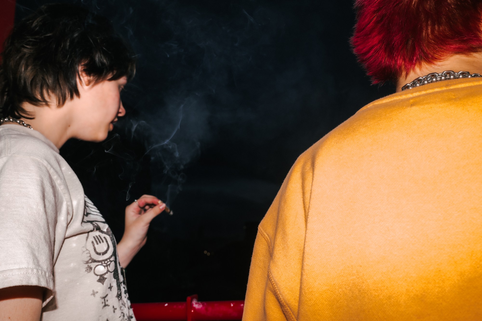 two girls with spiked hair smoking a cigarette at night in utah by blake lewis