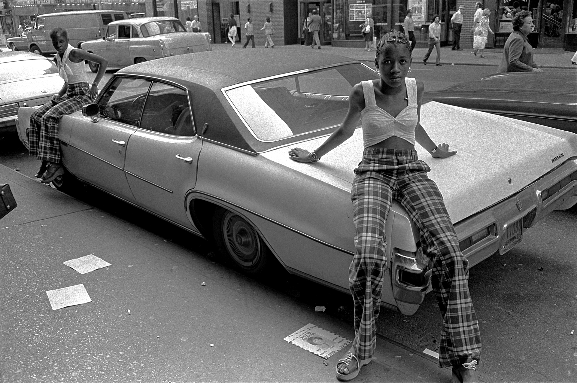 twin girls in matching outfits sit either side of a car