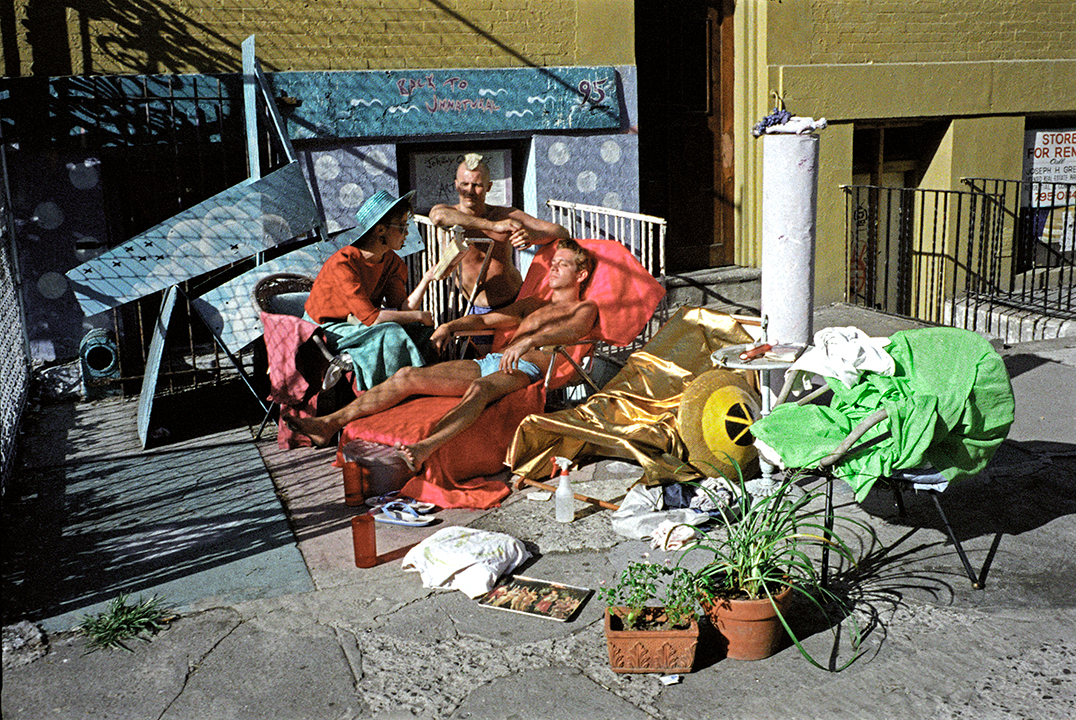 two men and a woman sit on chairs in the sun