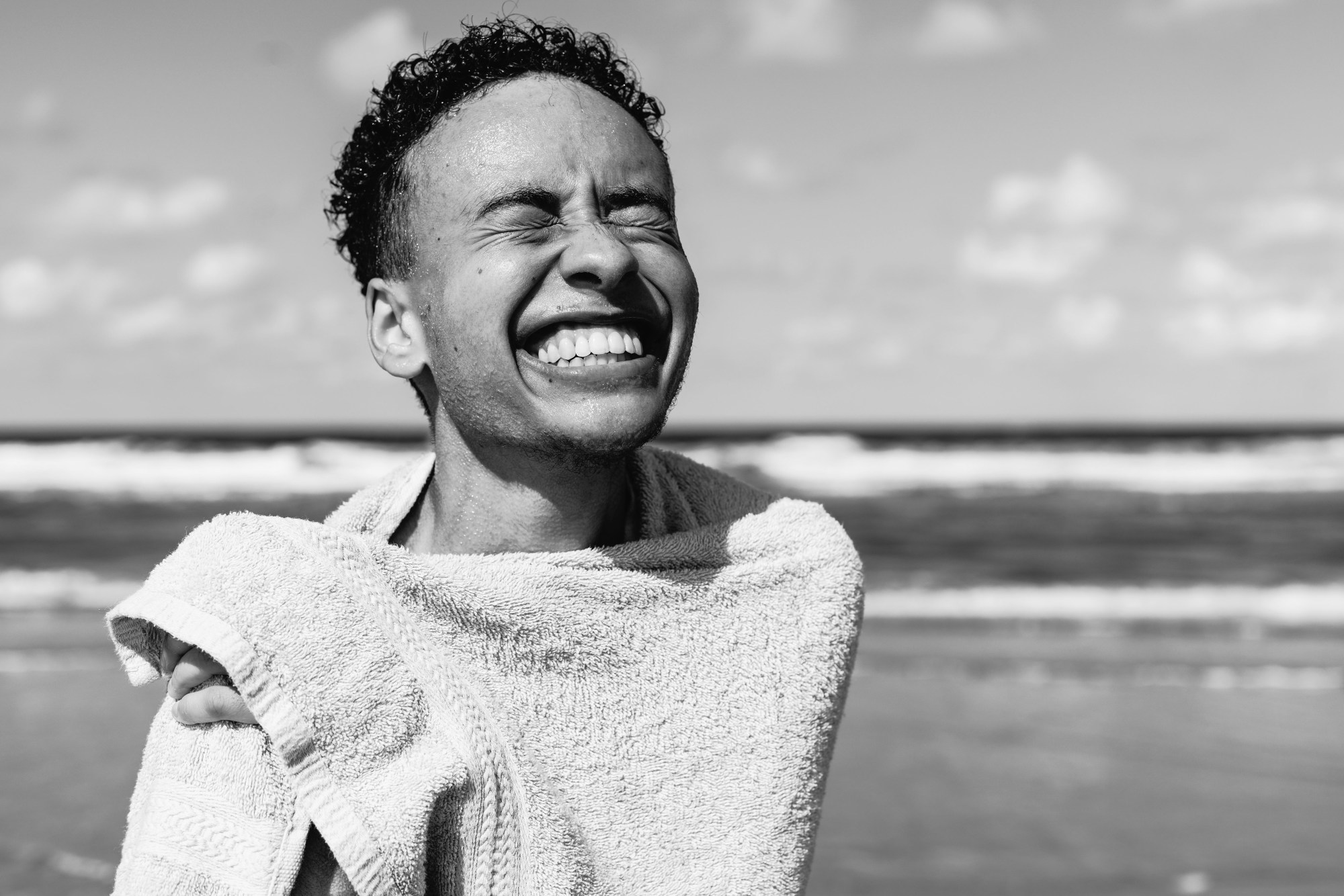 a person at the beach covered in a towel and smiling