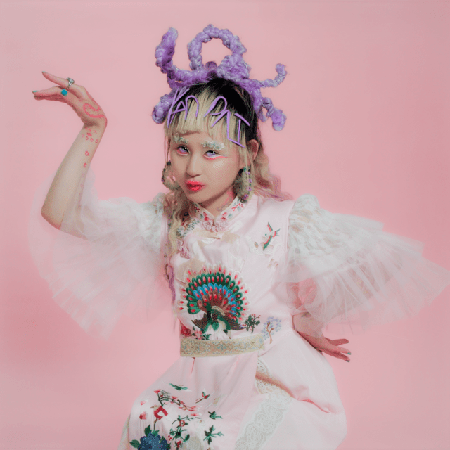 Alice Longyu Gao with a purple headpiece and her arms outstretched sideways