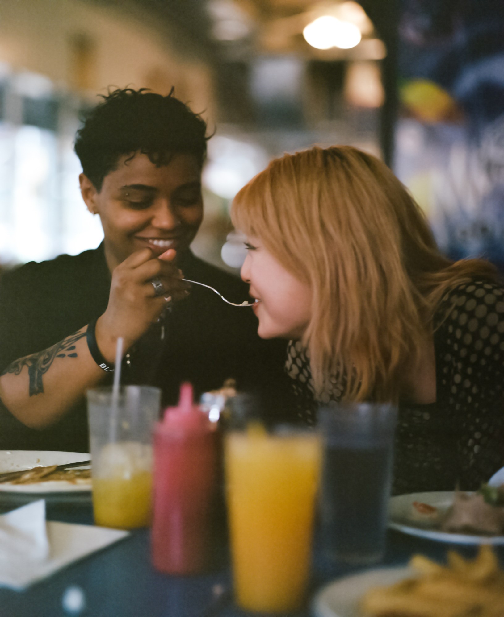 a person feeds another a mouthful of food in a restaurant