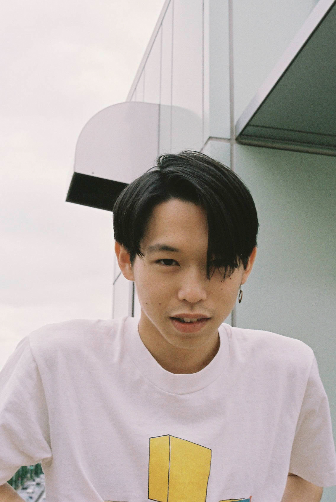 a young man wearing a white t-shirt with a yellow cube on it