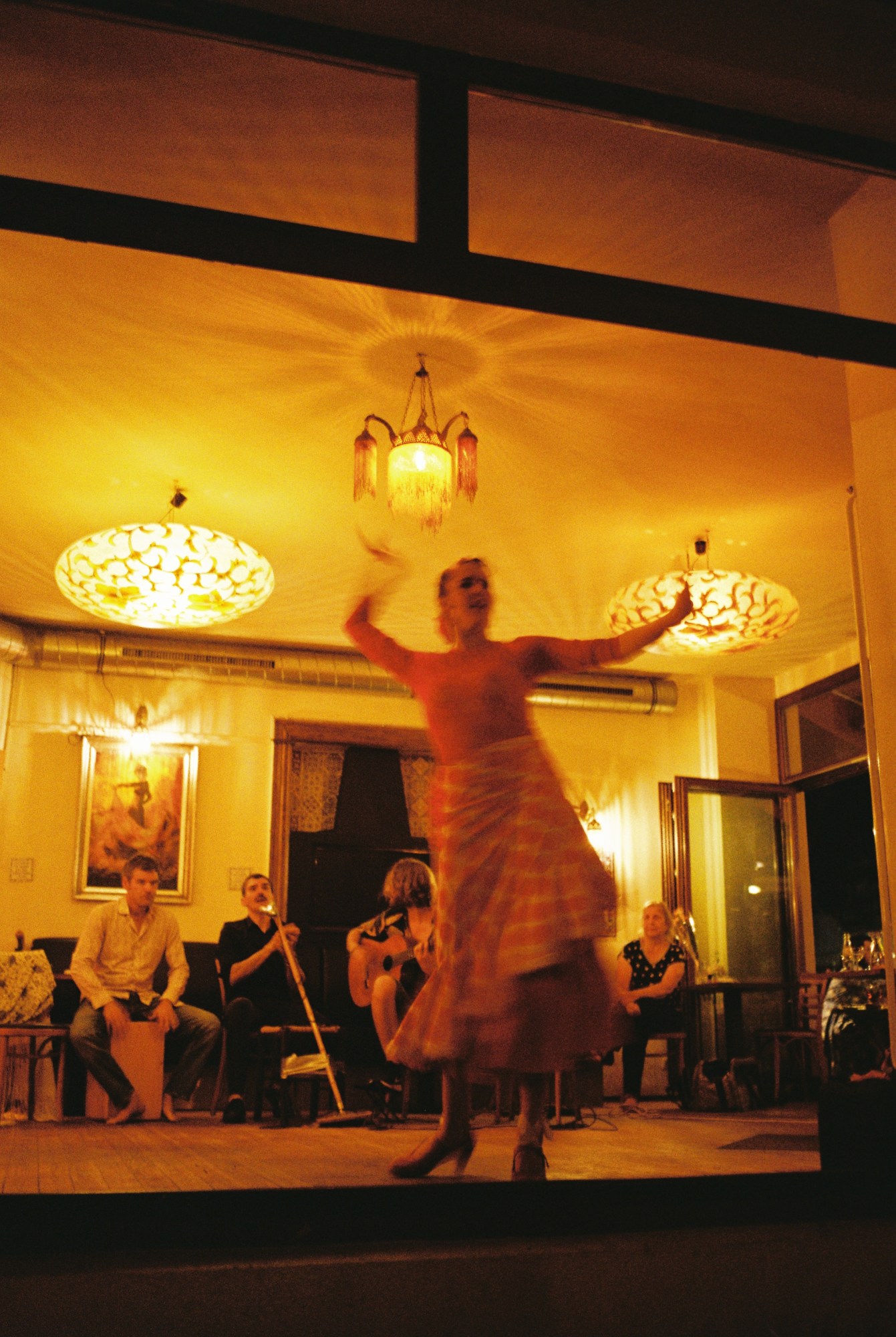 A flamenco dancer moves around a restaurant floor as guests watch behind her.