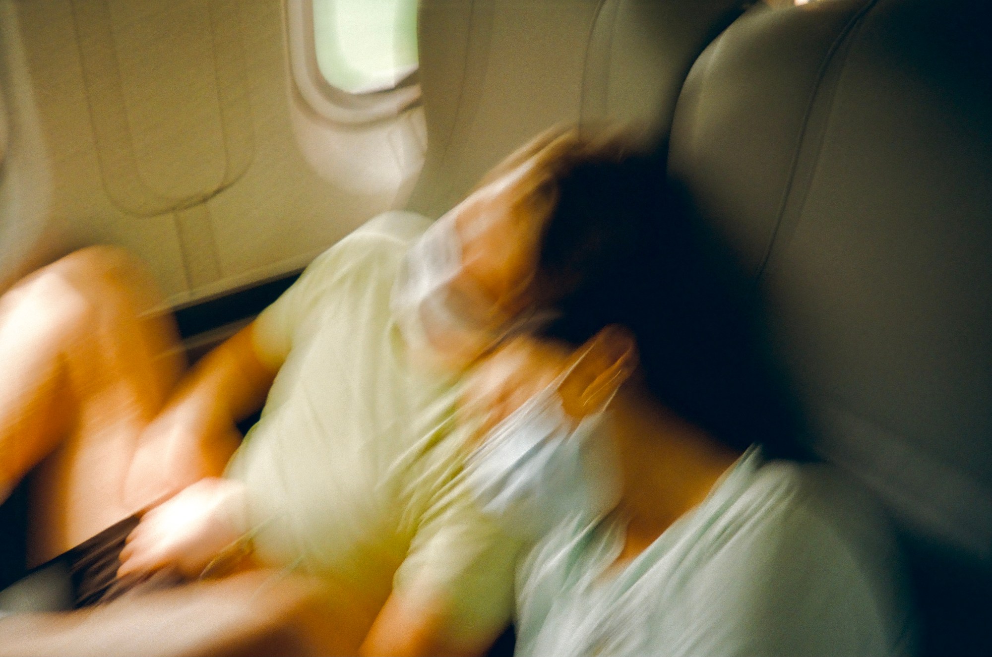 Blurred photo of two animated people wearing masks as they travel on the train.