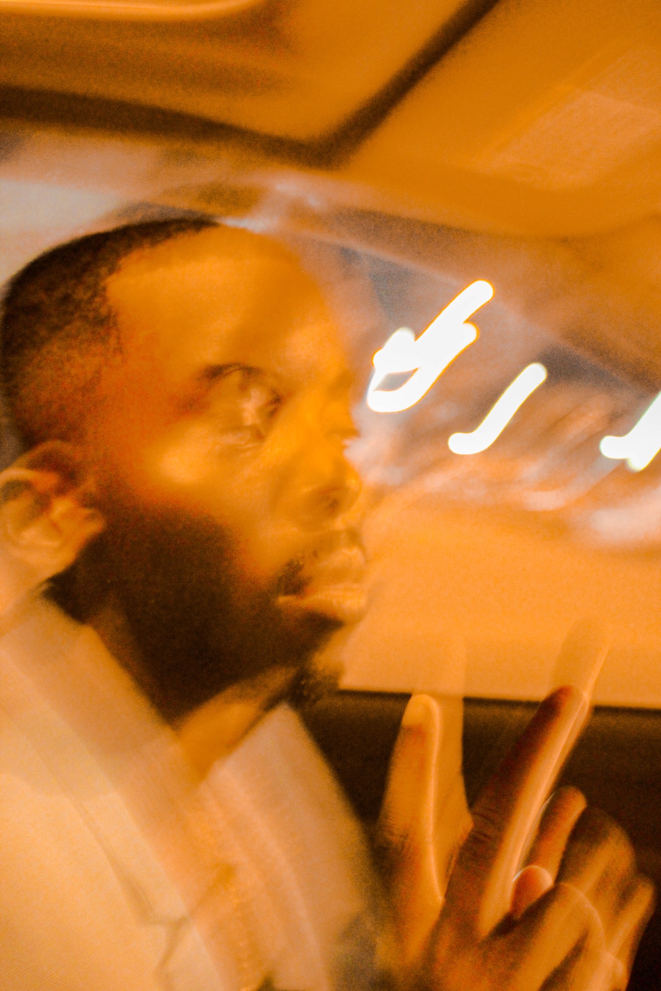 Blurred photo of a man sitting in a car doing the peace sign.