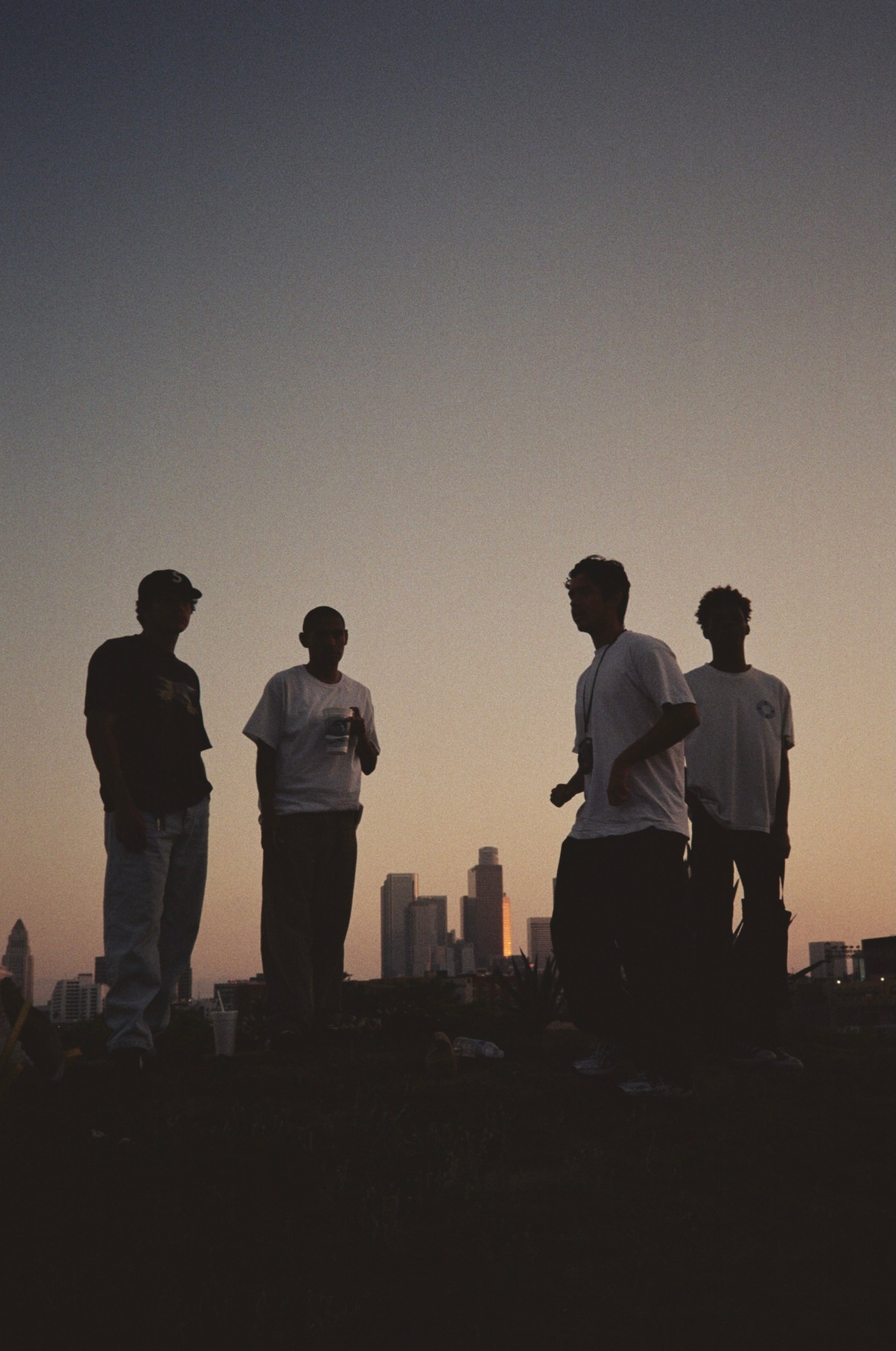 four men stand in front of skyscrapers in the distance.