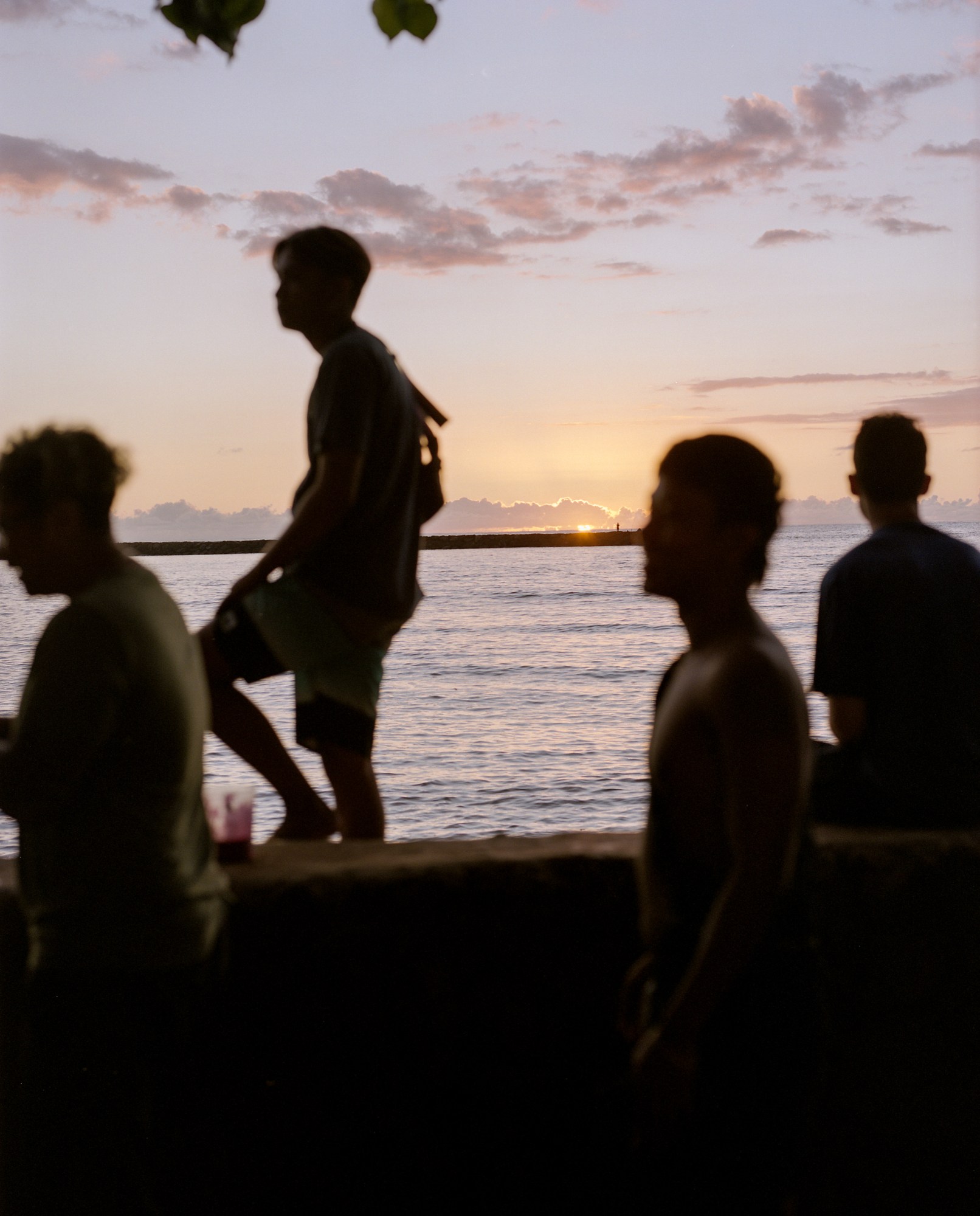 The silhouette of four people standing in front of a beach at sunset