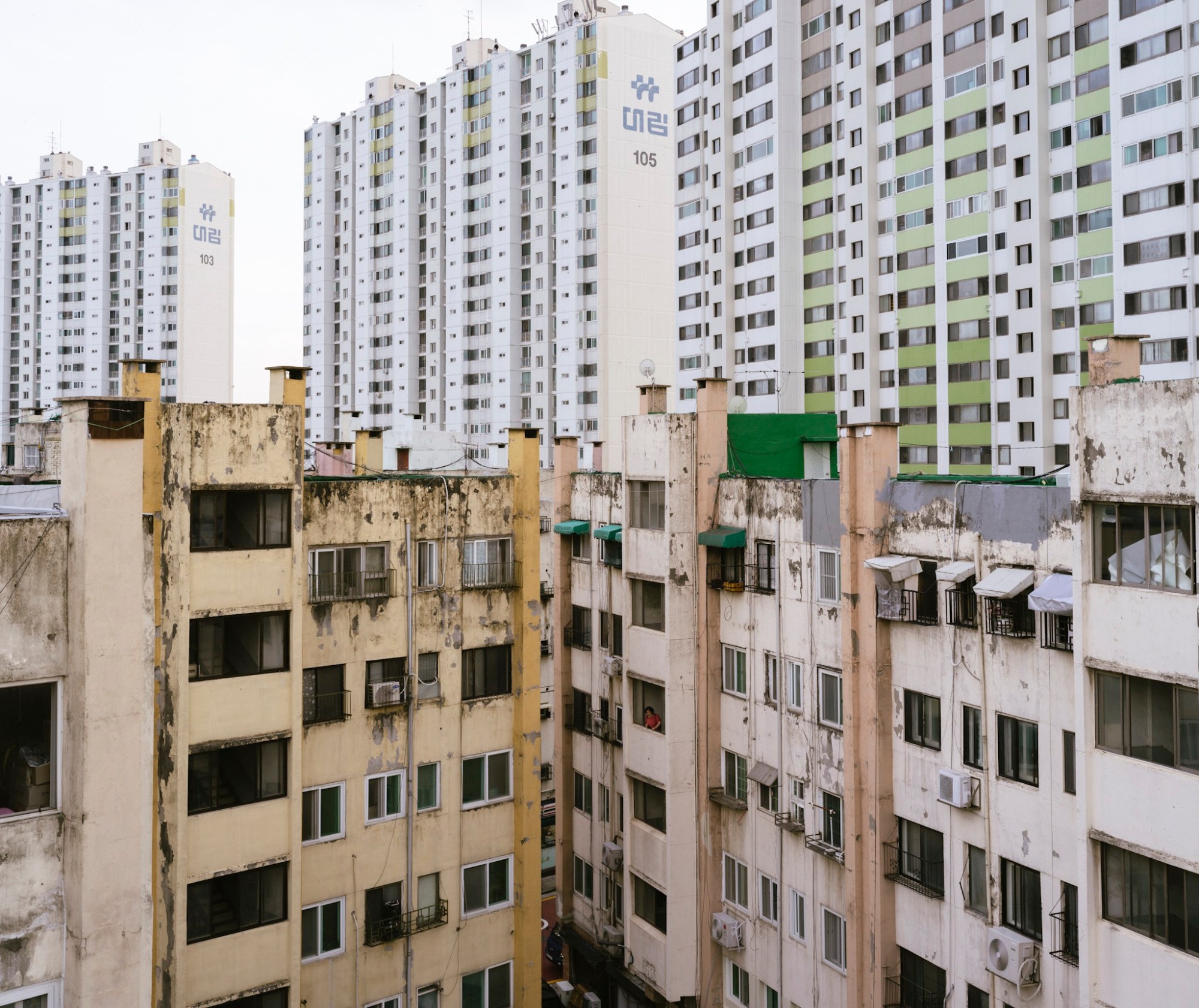 Old apartment buildings are in the foreground with new skyscraper buildings towering over behind them.