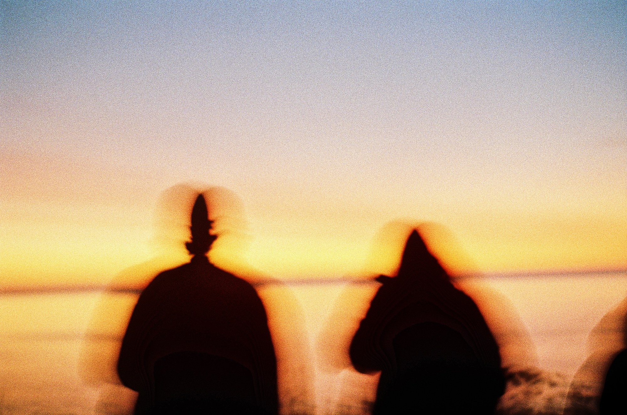 Blurred photo of two people in front of the sunset.