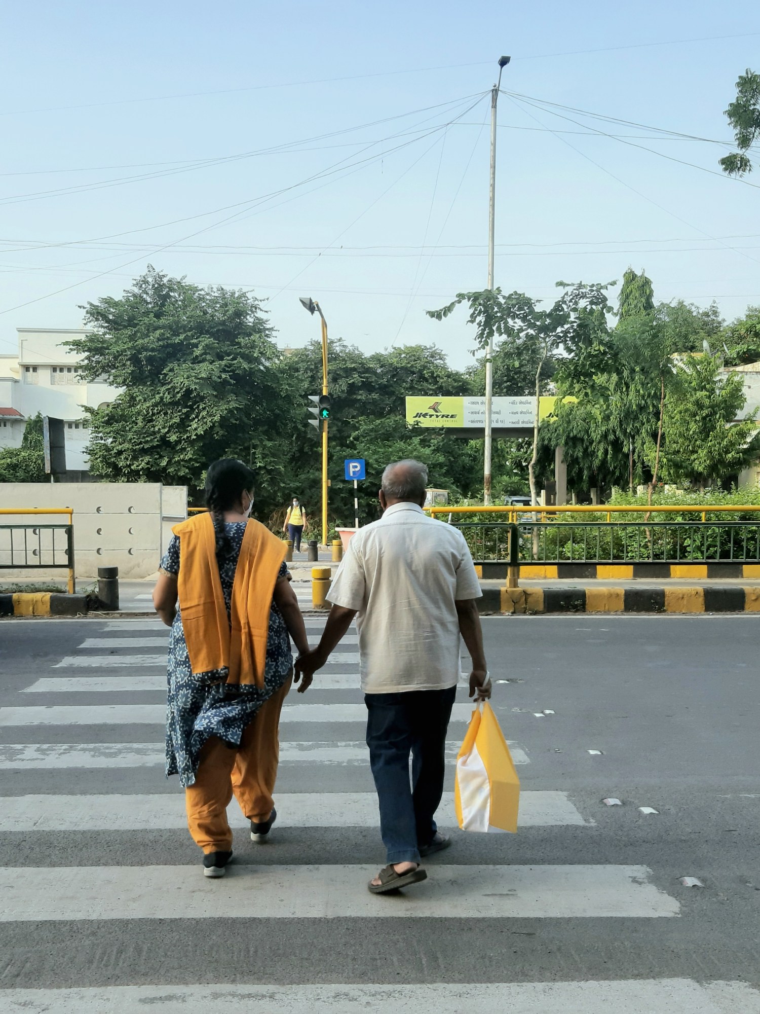 A couple hold hands as they cross the street.