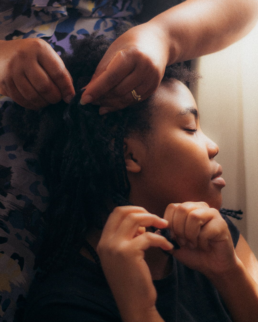 A mother undoes the hair of a young girl.