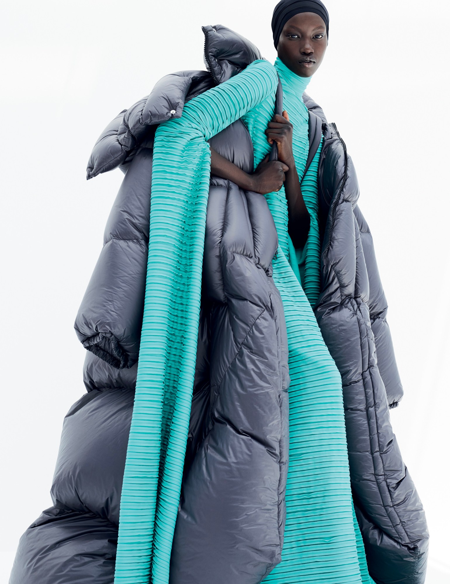 a model wears a long aqua dress under an oversized puffer jacket