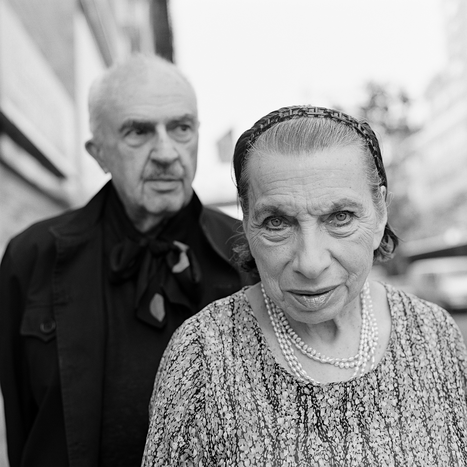 an man wearing a neck tie and a woman wearing a headband and peal necklace