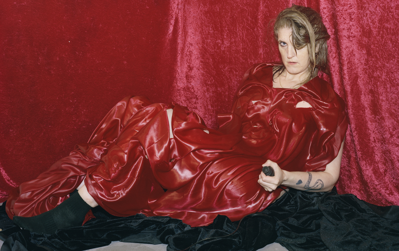 a woman in all red poses in front of a red velvet backdrop