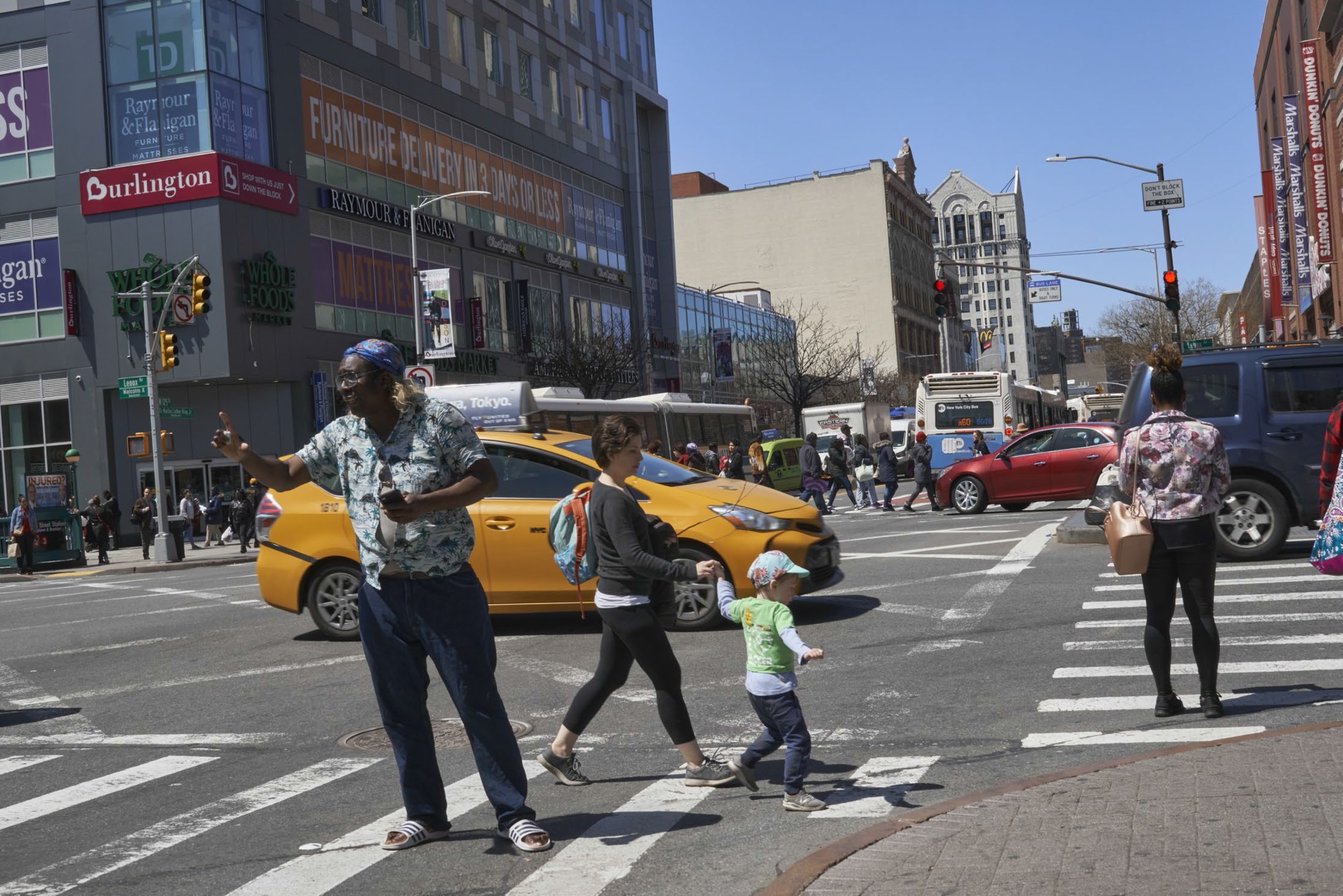 a man stands in the road in new york while people walk past