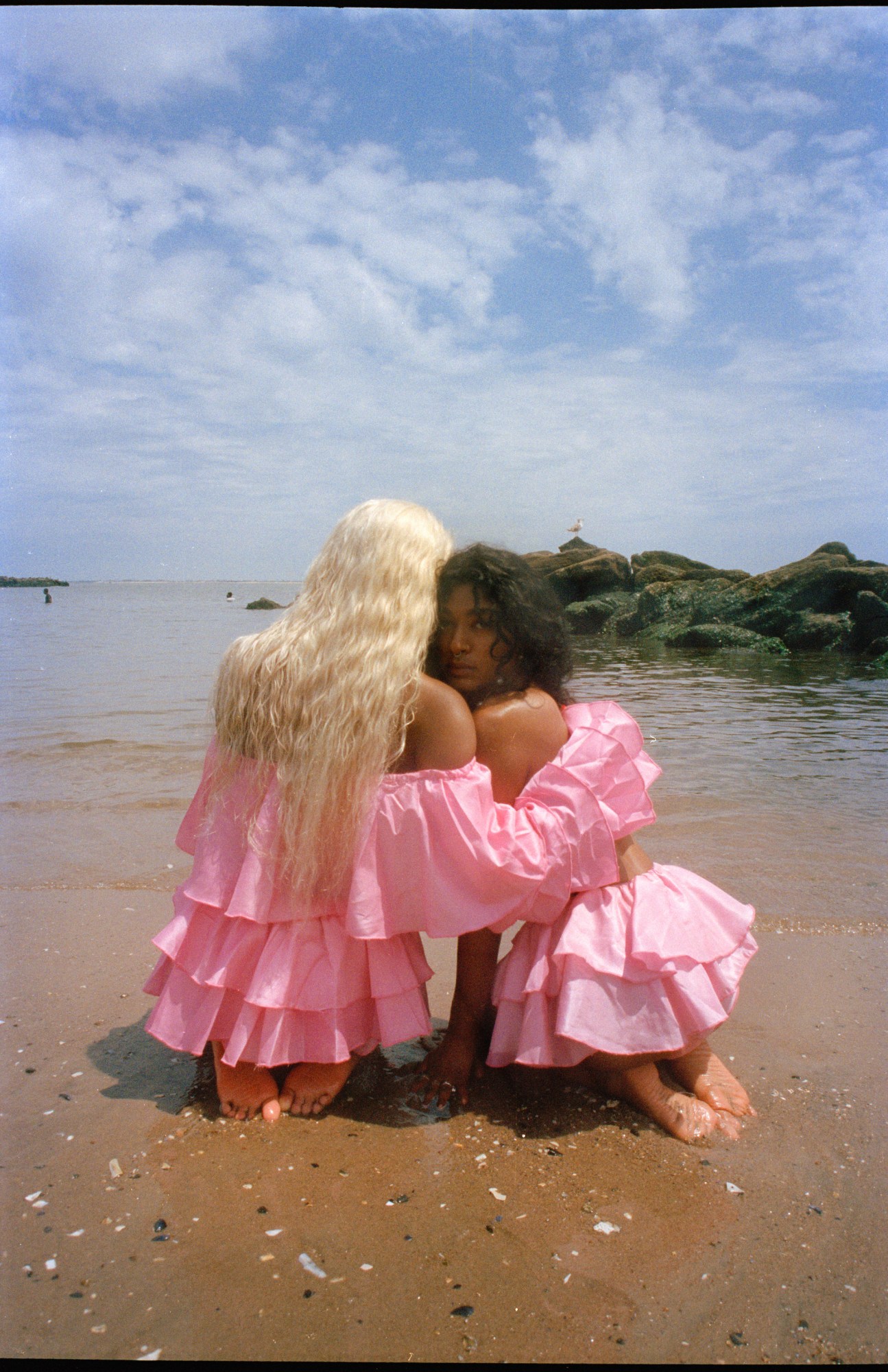 two girls sitting on a beach wearing pink by sophia wilson