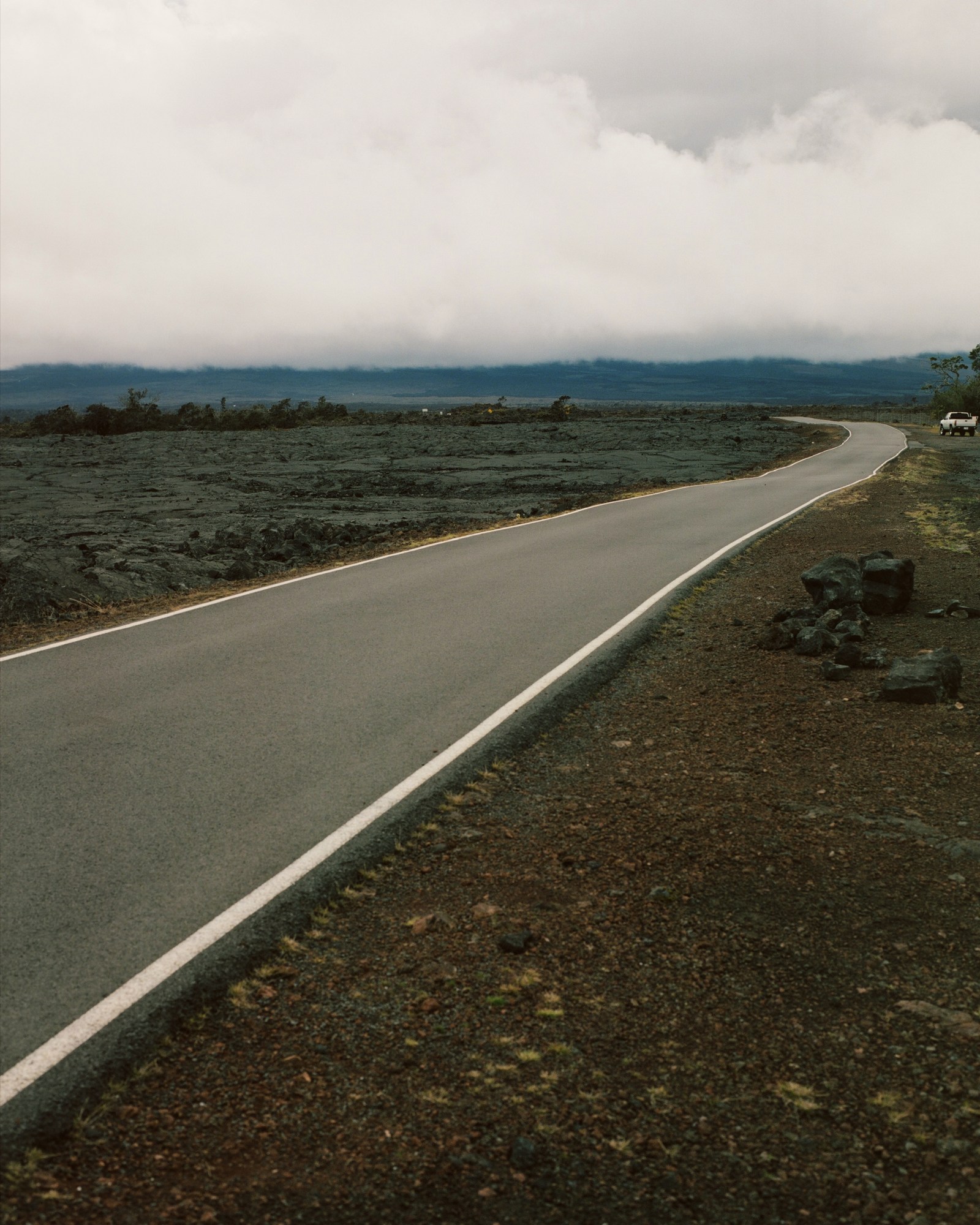 a dark grey landscape with a road running through the middle