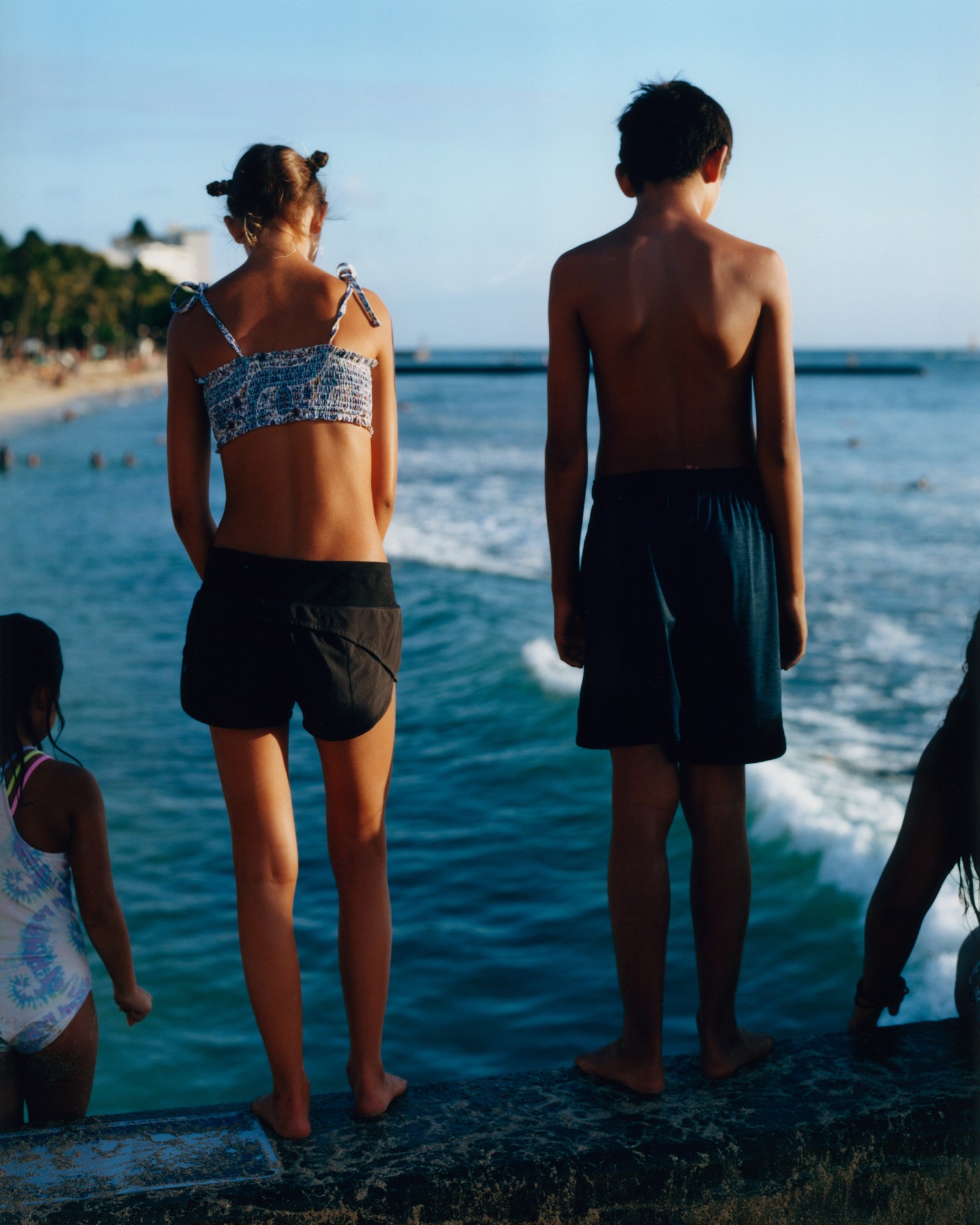 kids looks out over the sea from a high up ledge