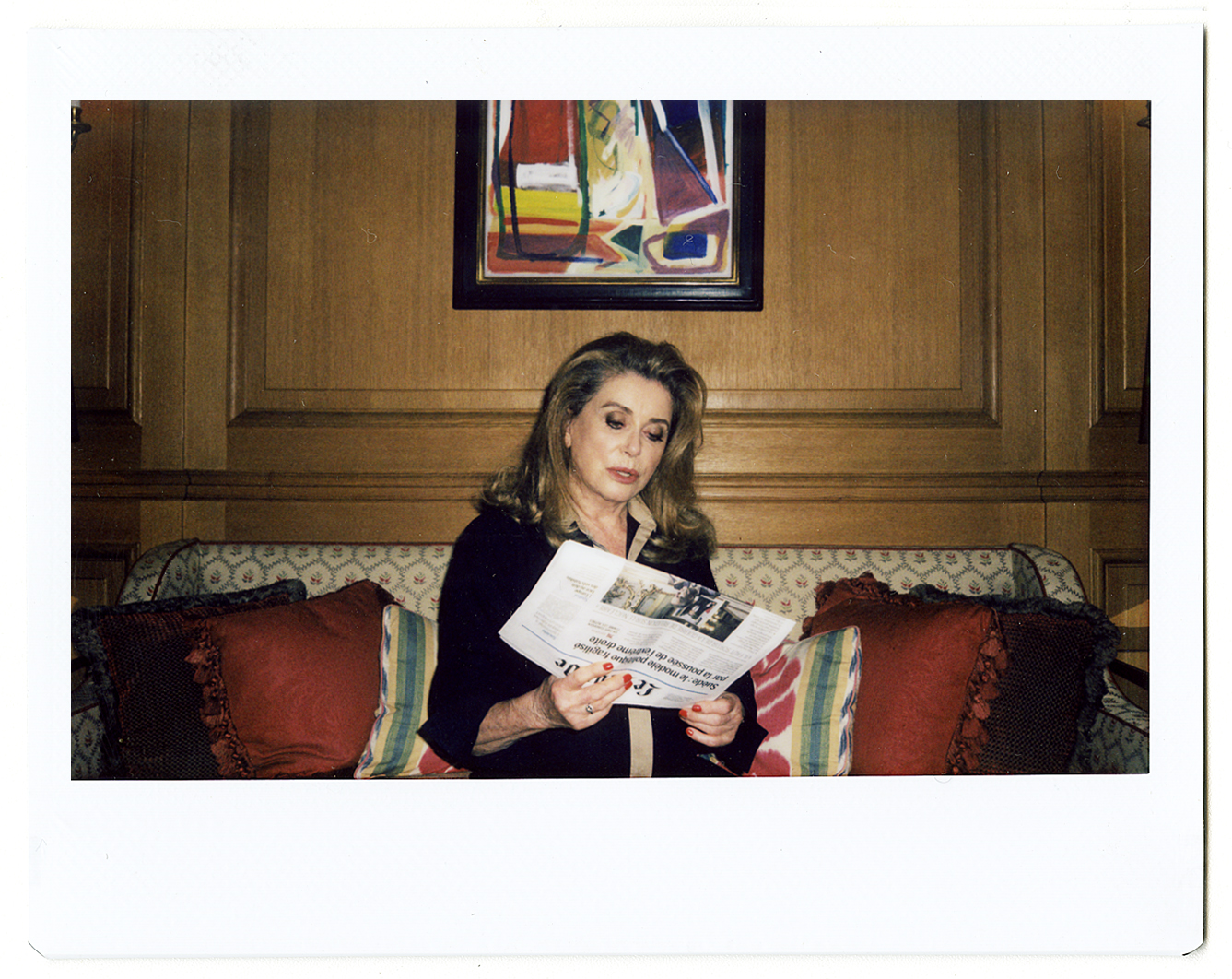 a polaroid portrait of catherine deneuve reading the paper by hugo huerta marin