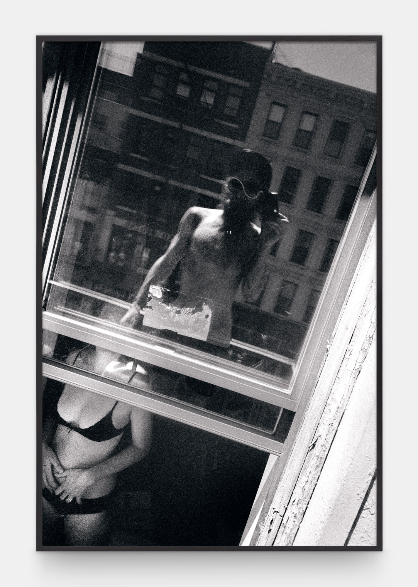 a man takes a picture of a woman in her underwear in a window, catching his own reflection