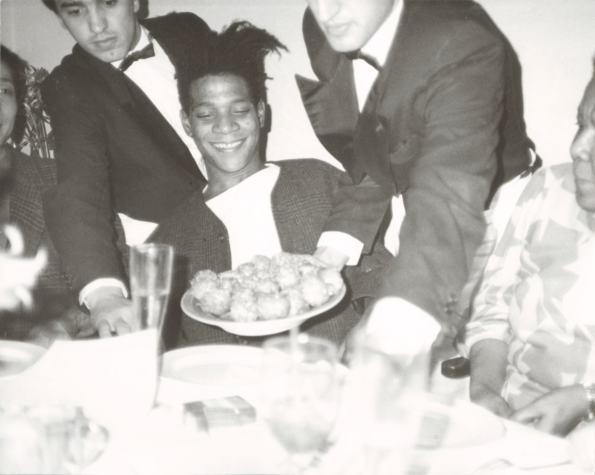 a photograph of jean-michel basquiat eating dinner by andy warhol