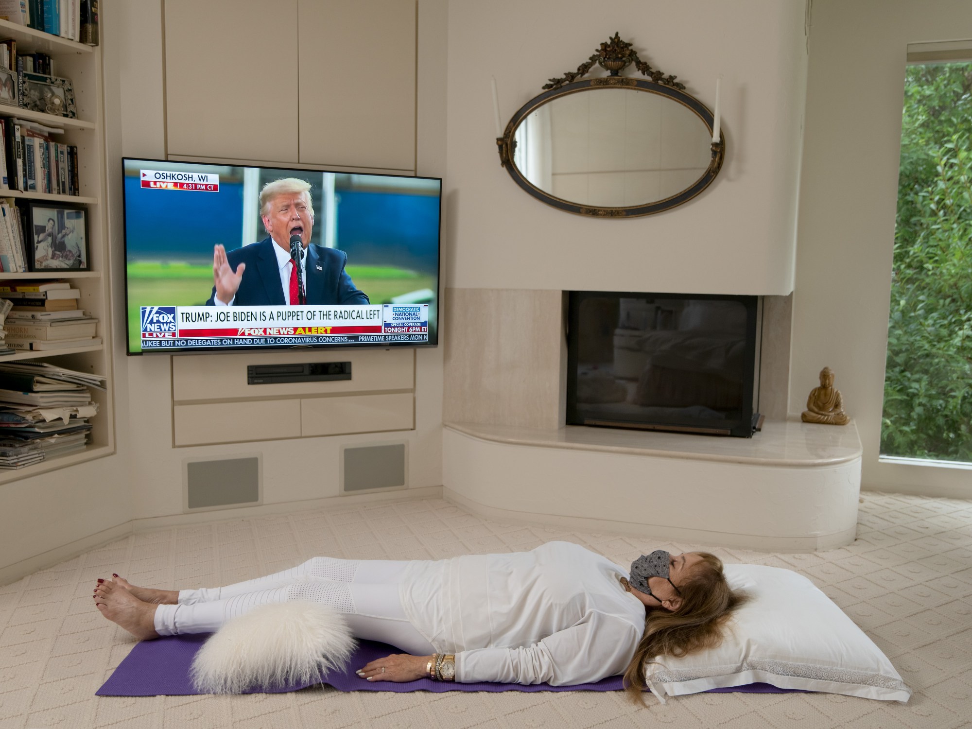 a woman lies on the floor as the tv plays fox news with trump on screen