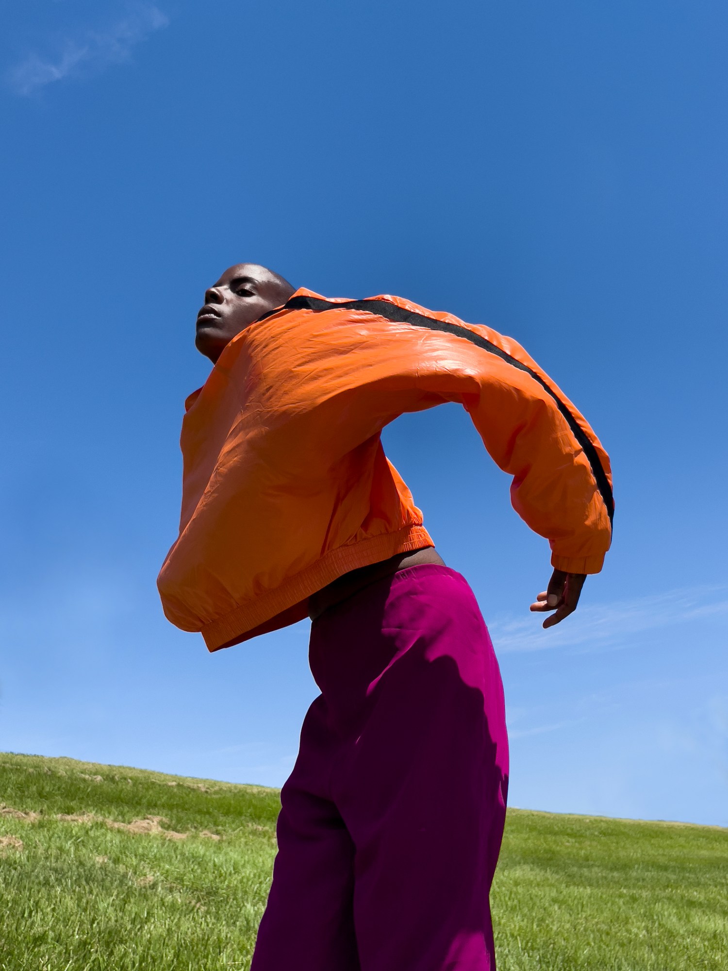 a portrait of a woman in a grassy field wearing bright colors by arielle bobb-willis