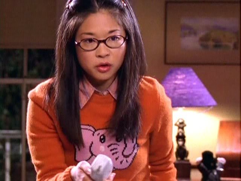 lane kim from gilmore girls wearing an orange sweater with a pink elephant on it