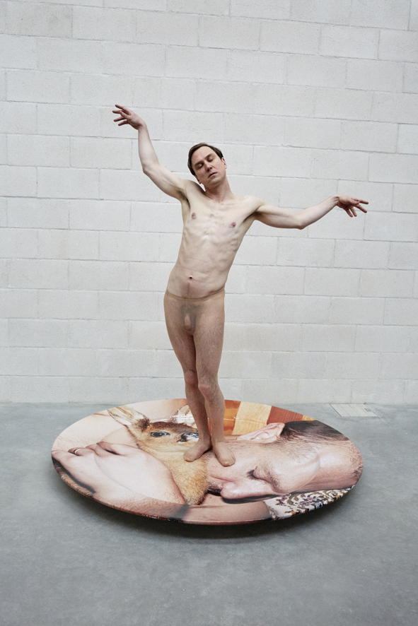 a man standing naked in tights of a giant plate